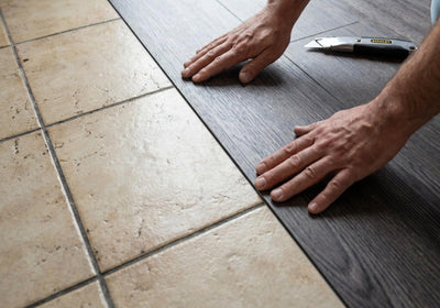 Hands pressing a self adhesive vinyl plank down over old tile